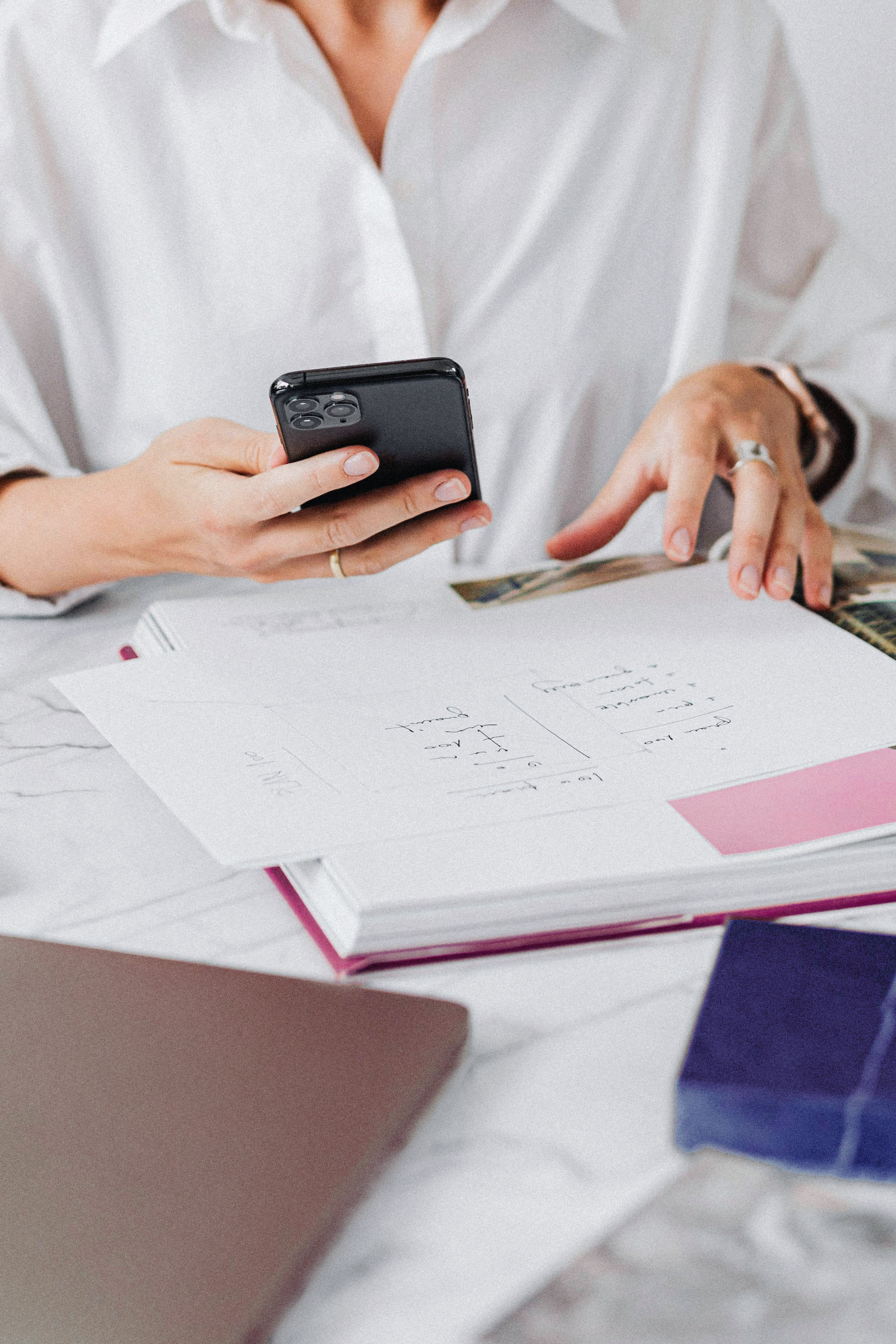 Women sitting at desk with phone in hand and book in front of her