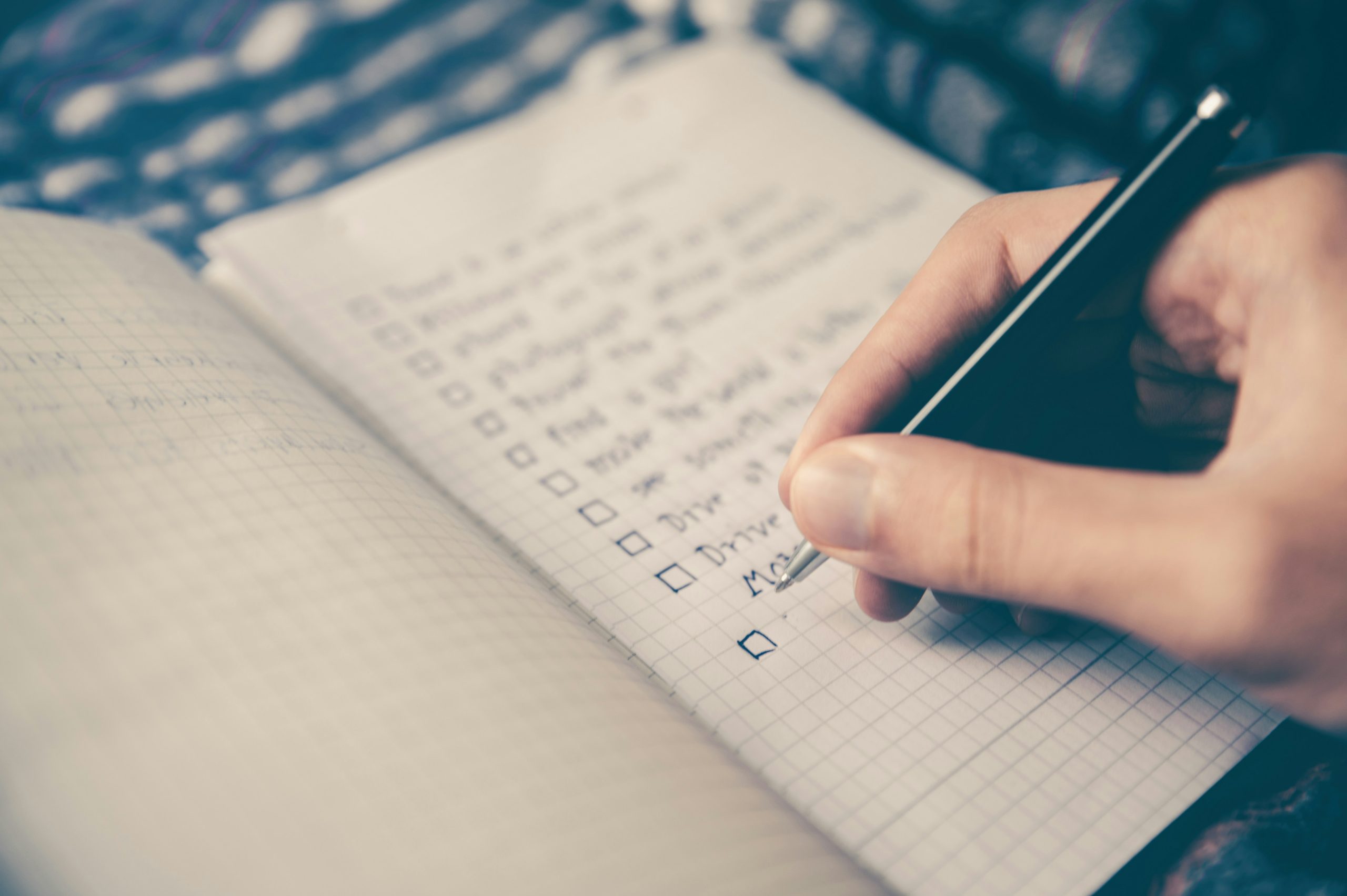 Notebook open with a checklist, a hand holding a pen