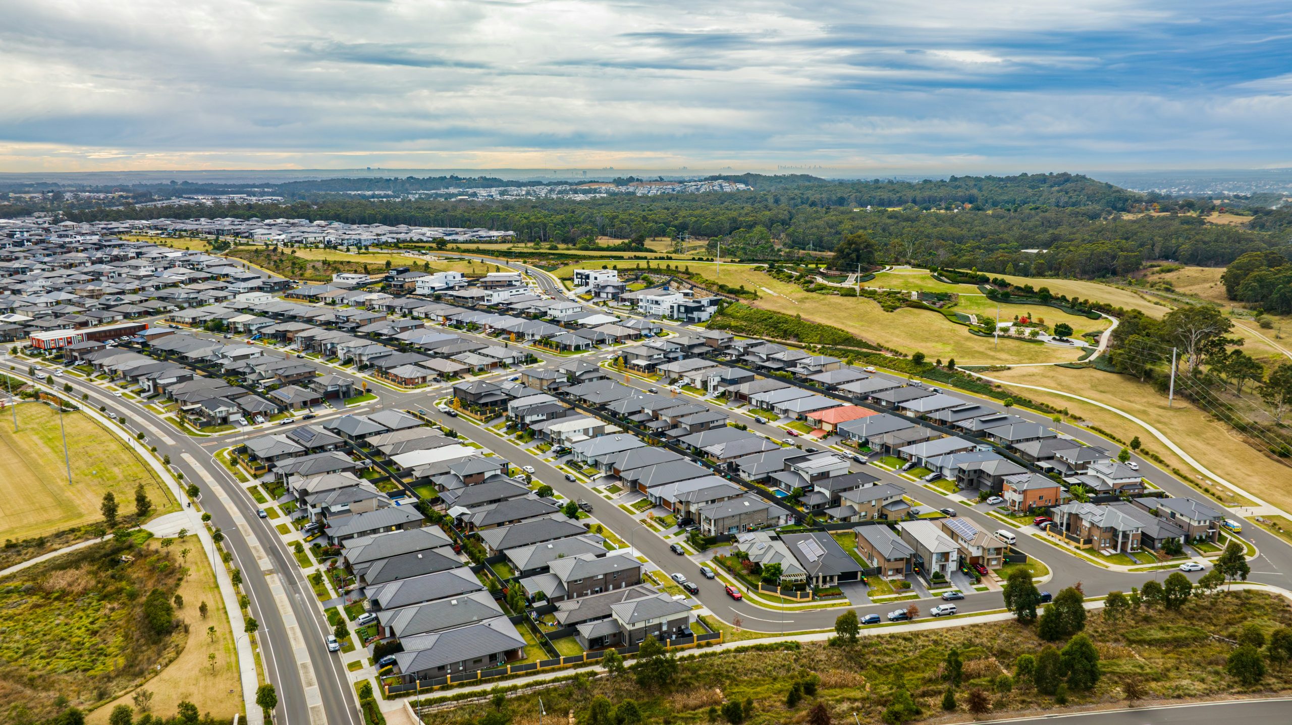 Aerial view of a modern residential estate with new homes, roads and surrounding parkland.
