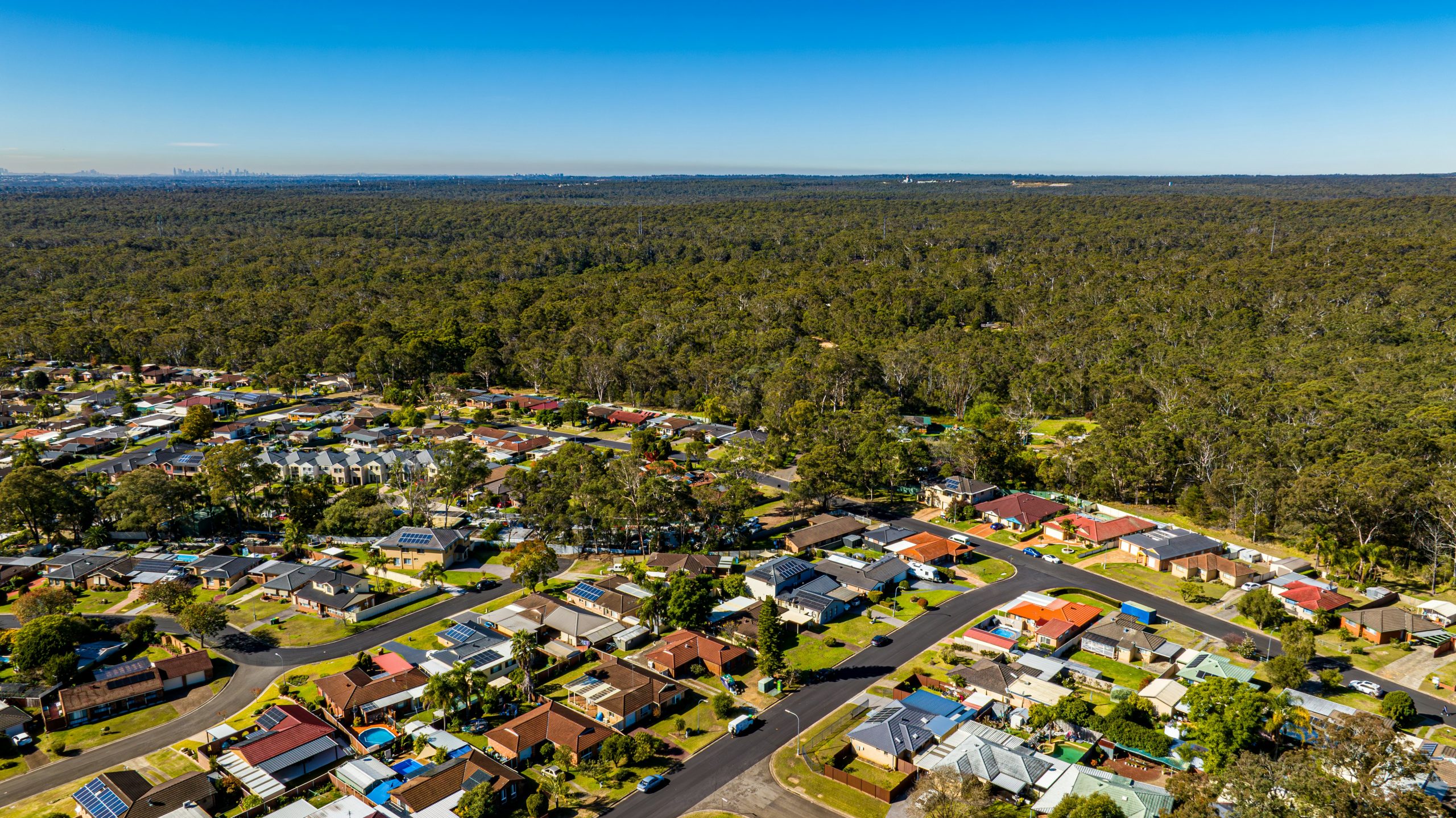 Aerial view of a modern residential estate with new homes, roads and surrounding parkland.