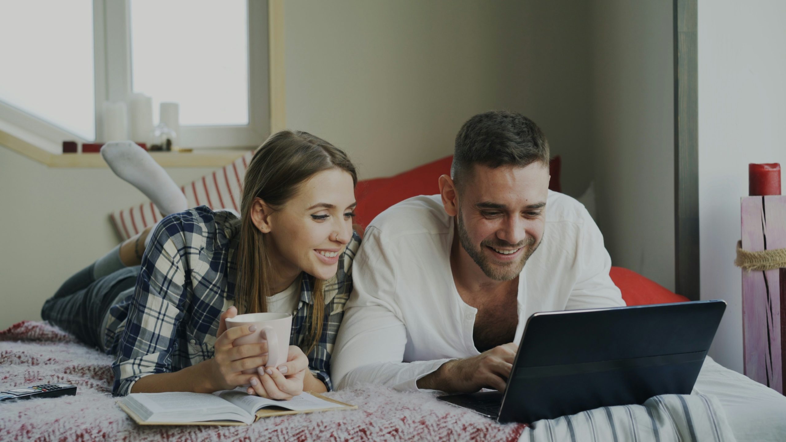 Young couple relaxing at home while looking at a laptop together.